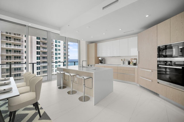 kitchen featuring visible vents, modern cabinets, light countertops, light brown cabinets, and stainless steel oven