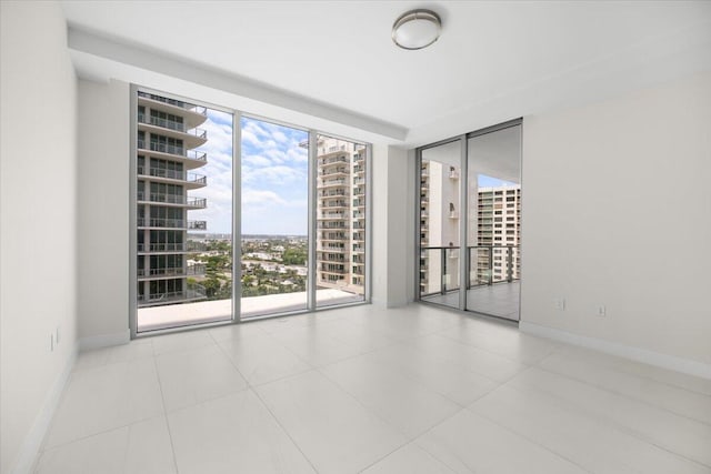 unfurnished room featuring a view of city, expansive windows, and baseboards