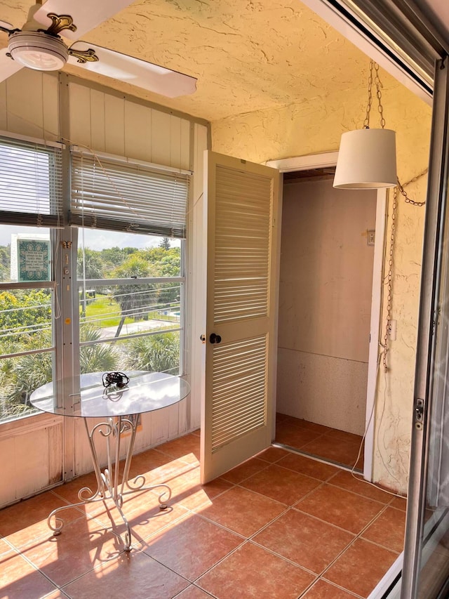 unfurnished sunroom with ceiling fan