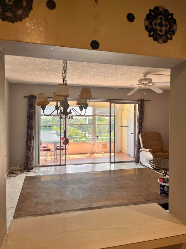 unfurnished dining area with a textured ceiling, light tile patterned floors, and ceiling fan with notable chandelier