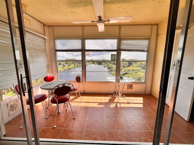 unfurnished sunroom with a water view and ceiling fan