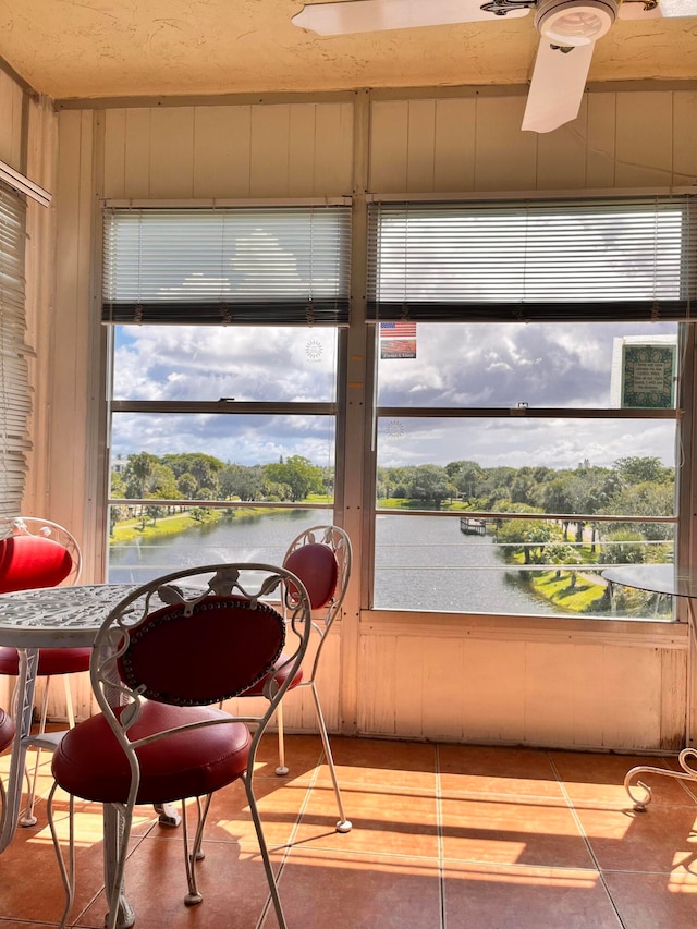 sunroom with a water view, ceiling fan, and a wealth of natural light