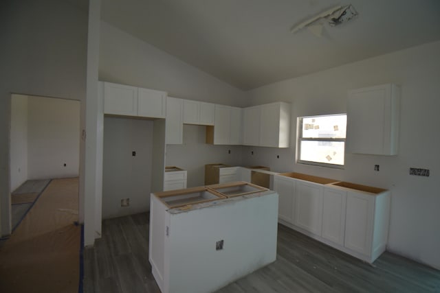 kitchen featuring lofted ceiling, a kitchen island, white cabinets, and dark wood-type flooring