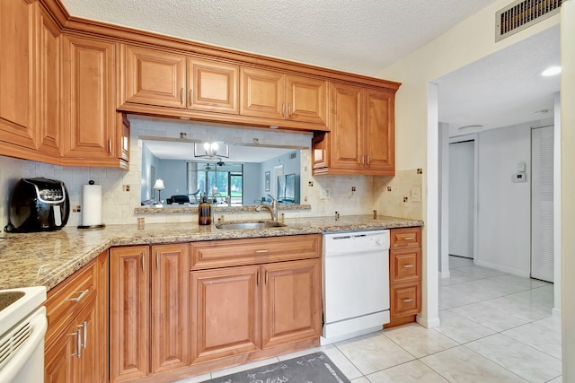 kitchen featuring white appliances, a textured ceiling, sink, light stone countertops, and light tile patterned flooring