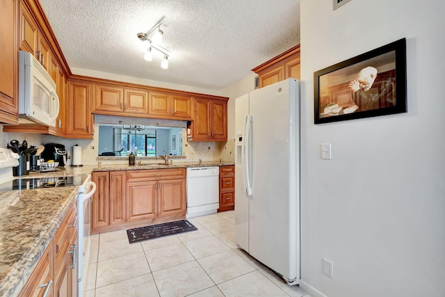 kitchen with white appliances, a textured ceiling, light tile patterned floors, light stone counters, and sink