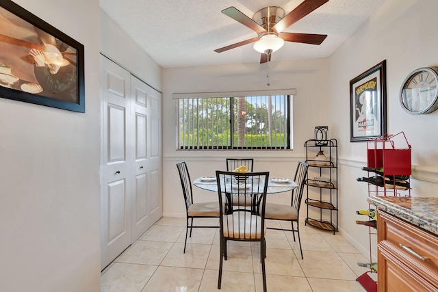 dining space with a textured ceiling, ceiling fan, and light tile patterned floors