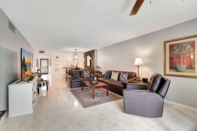 tiled living room featuring ceiling fan and a textured ceiling