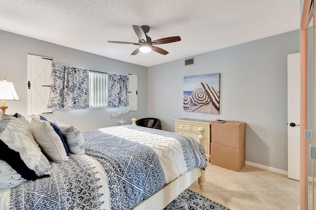 bedroom with a textured ceiling, ceiling fan, and light tile patterned flooring