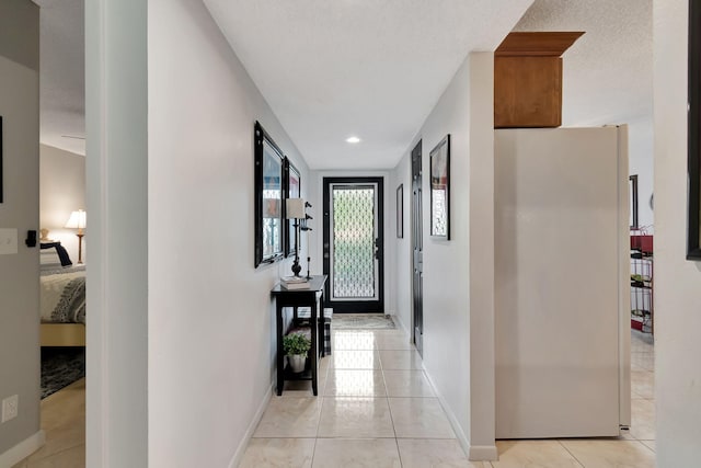 corridor featuring a textured ceiling and light tile patterned flooring