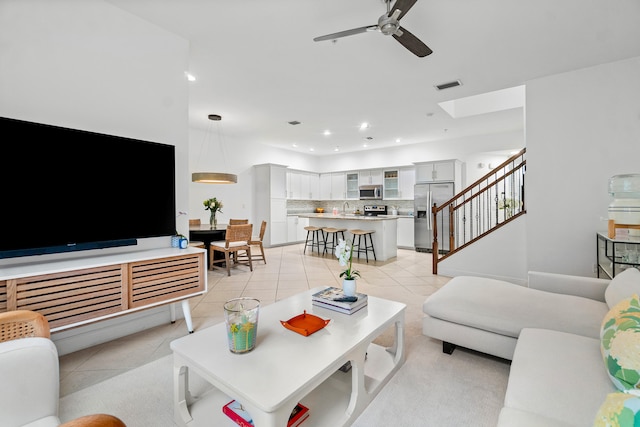 living room with ceiling fan, sink, and light tile patterned floors