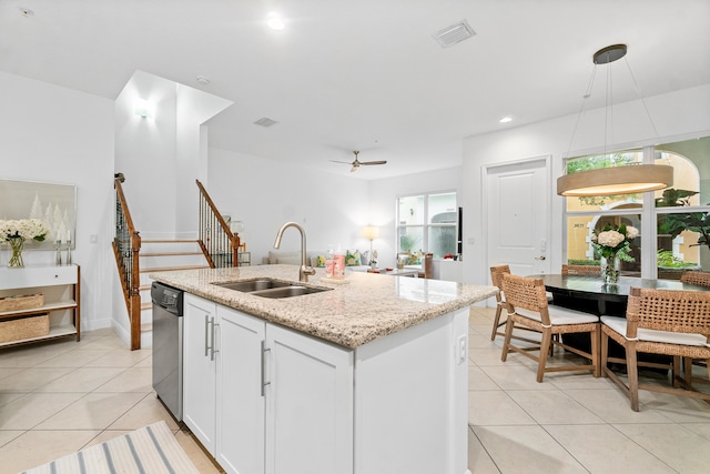 kitchen featuring sink, decorative light fixtures, light tile patterned floors, white cabinetry, and light stone counters