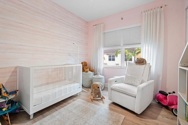 bedroom with light hardwood / wood-style floors and a crib