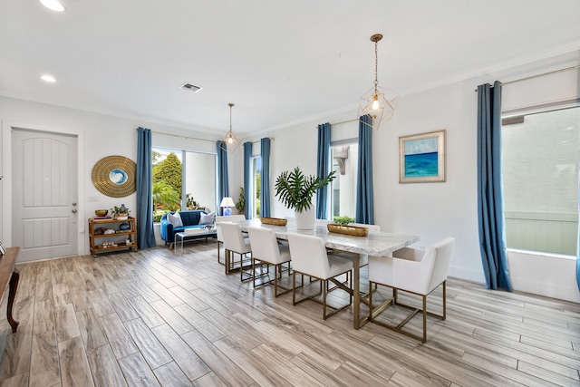 dining room with light wood-type flooring and crown molding