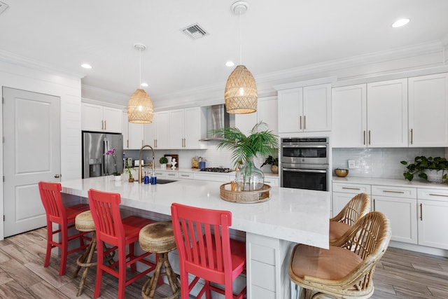 kitchen featuring a breakfast bar, sink, an island with sink, and appliances with stainless steel finishes