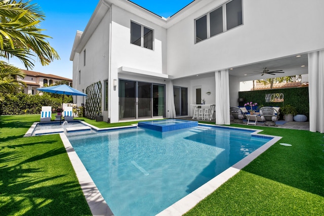 rear view of property featuring a lawn, ceiling fan, a swimming pool with hot tub, and an outdoor bar