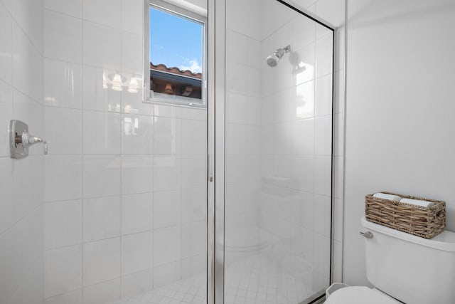 bathroom featuring a shower with shower door and toilet