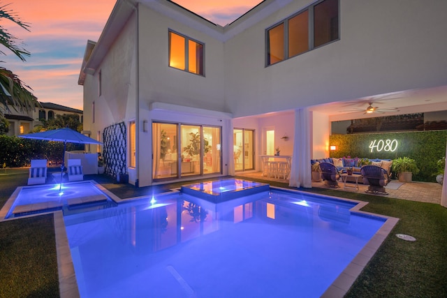 pool at dusk featuring a patio area, an in ground hot tub, ceiling fan, and an outdoor hangout area