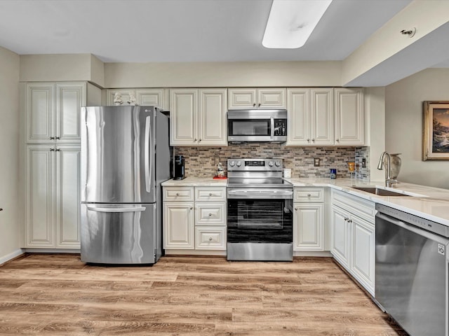 kitchen with sink, light hardwood / wood-style flooring, stainless steel appliances, and backsplash