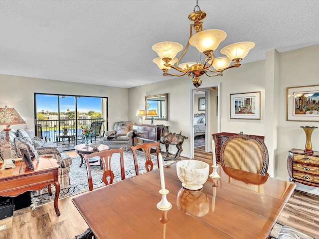 dining space featuring light hardwood / wood-style floors, a textured ceiling, and an inviting chandelier