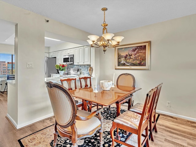 dining room featuring light hardwood / wood-style floors, an inviting chandelier, and a textured ceiling