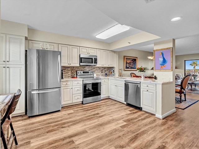 kitchen featuring decorative backsplash, white cabinetry, stainless steel appliances, and light hardwood / wood-style floors