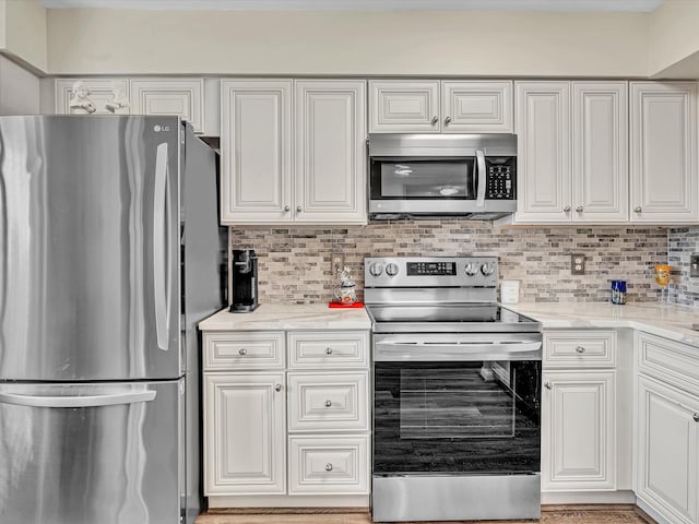 kitchen with light stone countertops, tasteful backsplash, appliances with stainless steel finishes, and white cabinets