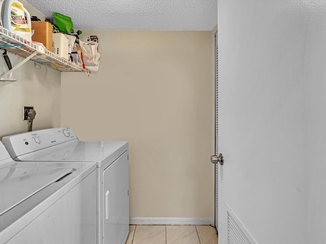 laundry area with independent washer and dryer, a textured ceiling, and light tile patterned floors