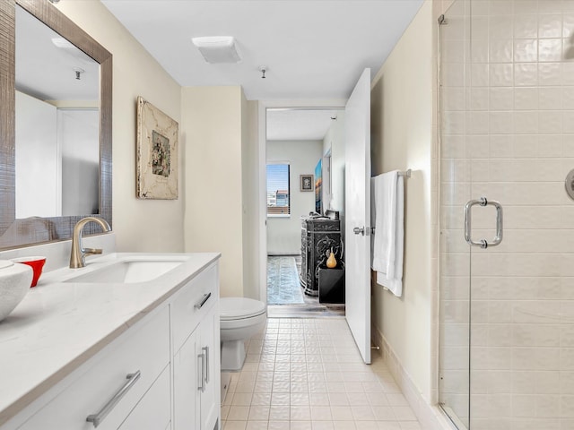 bathroom with a shower with door, vanity, toilet, and tile patterned floors