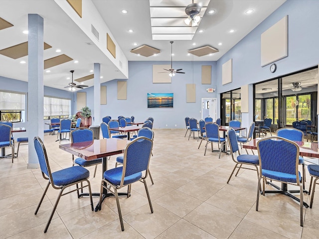 dining space featuring a towering ceiling, a healthy amount of sunlight, and light tile patterned floors