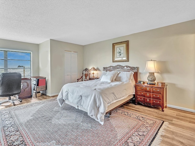 bedroom with light hardwood / wood-style flooring, a textured ceiling, and a closet