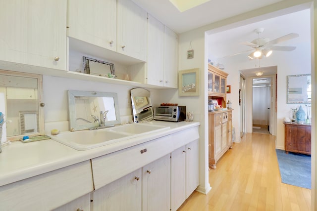 kitchen with white cabinets, ceiling fan, light wood-type flooring, and sink