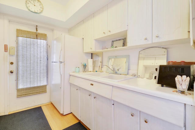 kitchen featuring light hardwood / wood-style floors, white cabinetry, white fridge, and sink