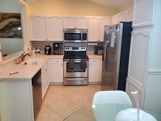 kitchen with white cabinets, vaulted ceiling, stainless steel appliances, and sink