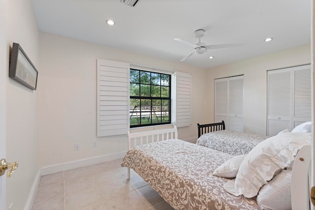 bedroom with two closets, ceiling fan, and light tile patterned floors