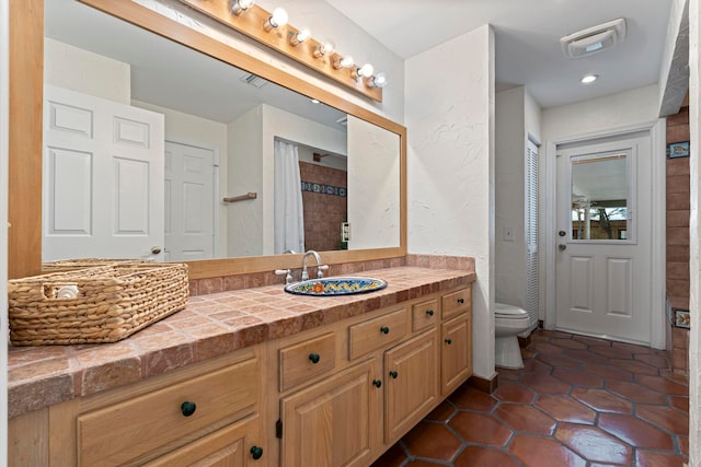 bathroom with vanity, toilet, walk in shower, and tile patterned floors