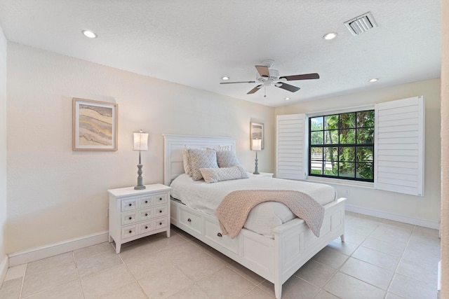 bedroom with a textured ceiling, light tile patterned floors, and ceiling fan