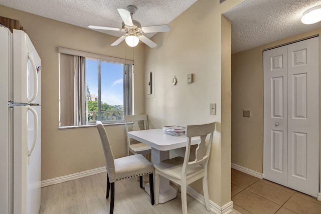 tiled dining room with a textured ceiling and ceiling fan