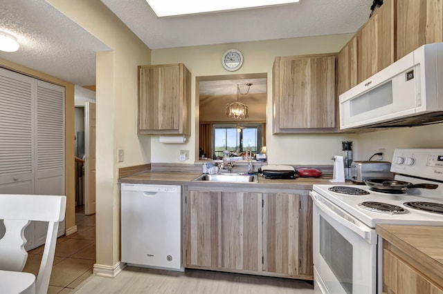 kitchen featuring sink, a notable chandelier, pendant lighting, a textured ceiling, and white appliances