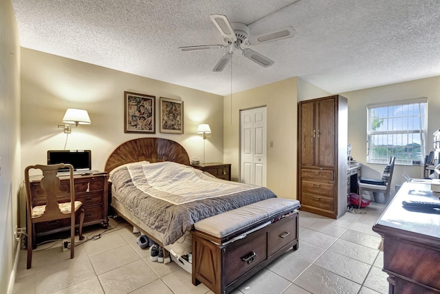 bedroom featuring a textured ceiling, a closet, ceiling fan, and light tile patterned flooring