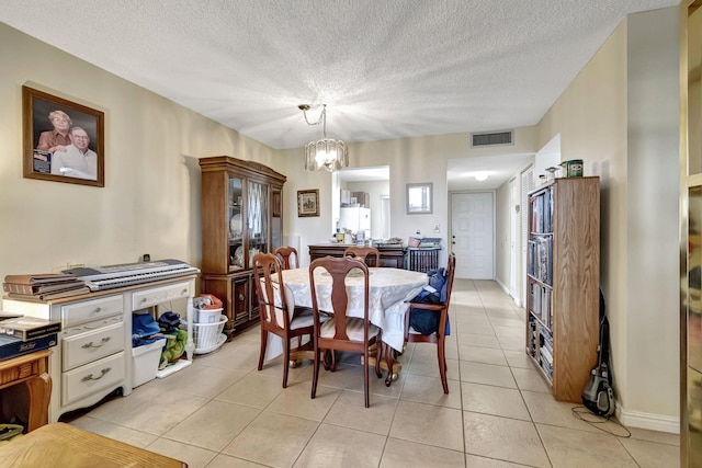 dining space with a textured ceiling, a notable chandelier, and light tile patterned flooring