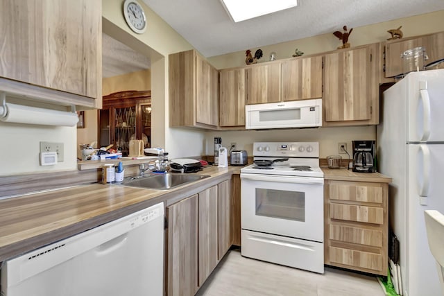 kitchen with a textured ceiling, white appliances, sink, and light brown cabinetry