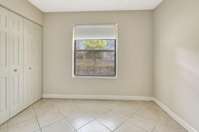 unfurnished bedroom with light tile patterned floors and a closet