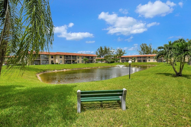 view of property's community with a water view and a lawn