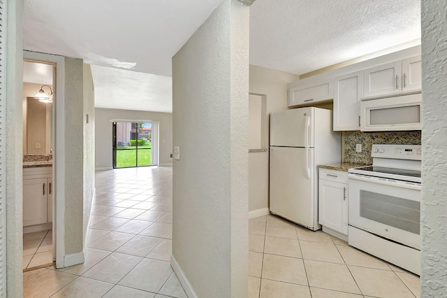 kitchen with white appliances, decorative backsplash, white cabinetry, light stone counters, and light tile patterned flooring