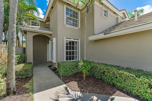 view of exterior entry featuring a tile roof and stucco siding