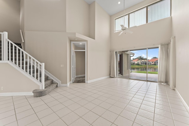 spare room featuring ceiling fan, light tile patterned floors, and a towering ceiling