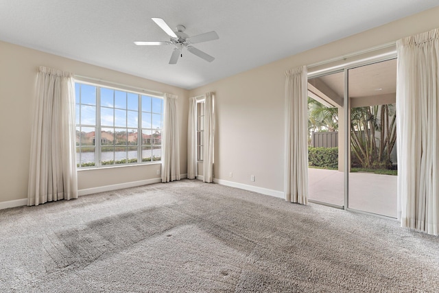 empty room featuring ceiling fan, light carpet, and a water view