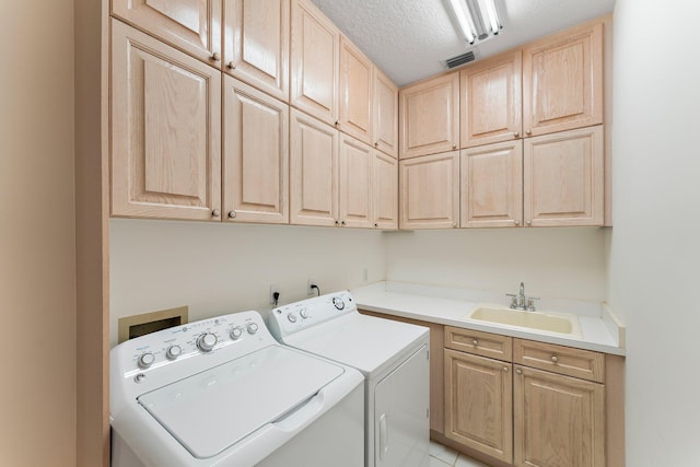 laundry room featuring a textured ceiling, cabinets, separate washer and dryer, sink, and light tile patterned flooring