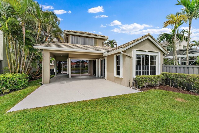 back of house with a lawn and a patio