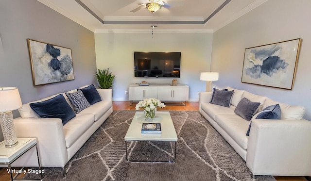 living room with a raised ceiling, crown molding, dark hardwood / wood-style flooring, and ceiling fan